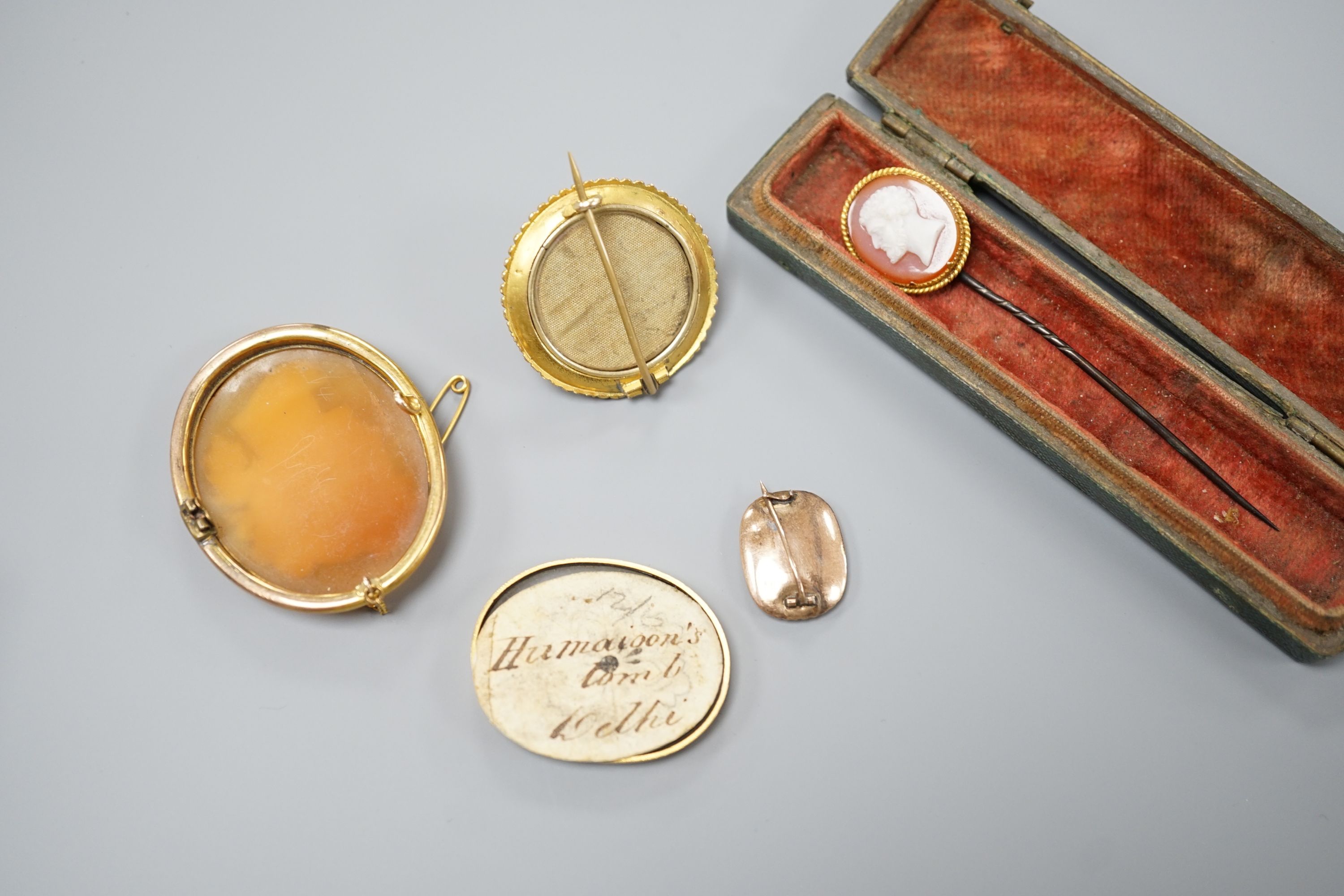 A Victorian yellow metal and cabochon garnet set circular brooch, 31mm, gross 9.3 grams, a stick pin with yellow metal and hardstone cameo set terminal, a mounted Indian miniature, a mounted cameo shell brooch and a Vict